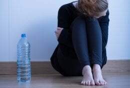 girl sitting on floor by wall with her head down