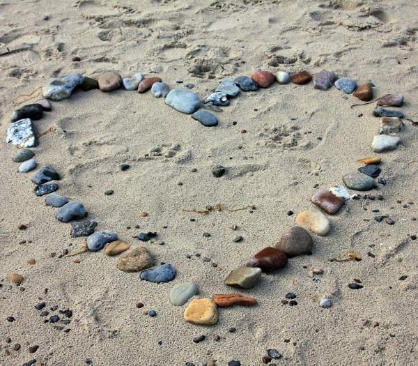 stones arranged in heart shape on sand