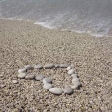 picture of heart made of stones on the beach near water